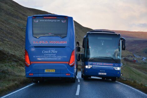 A blue bus driving down a road.