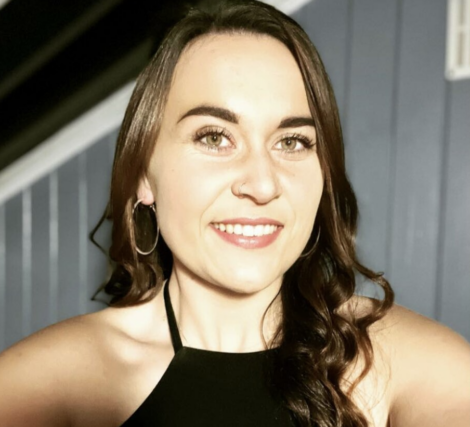 A woman in a black dress smiling for the camera.