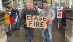 A man holding a sign that says case fire in front of a building.