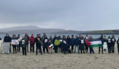 A group of people standing on a beach holding signs.