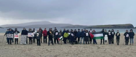 A group of people standing on a beach holding signs.