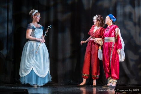 Three women dressed up in costumes on stage.