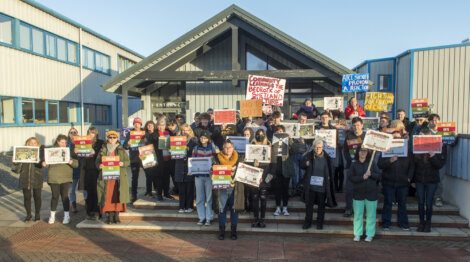 A group of people holding signs in front of a building.