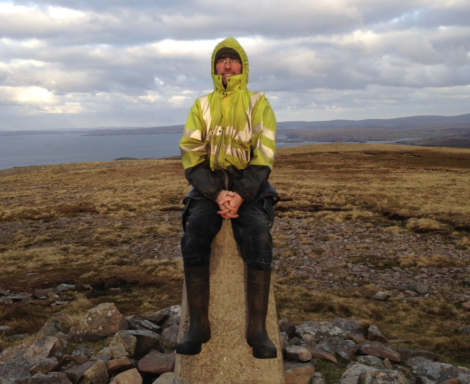 A man sitting on a stone pillar.