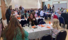 A group of people sitting at tables in a large hall.