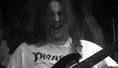 A man with long hair playing a bass.