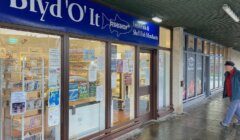 A man walks past a shop with a sign on it.