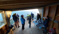 A group of people standing on a deck overlooking the ocean.