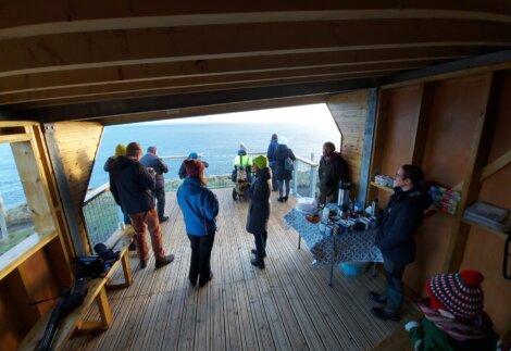 A group of people standing on a deck overlooking the ocean.