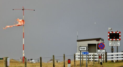 A red flag on a pole next to a sign.