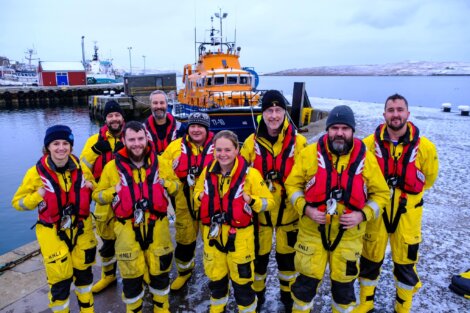 A group of people in yellow life jackets standing next to a boat.