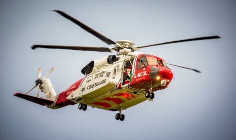 A red and white helicopter flying through the sky.