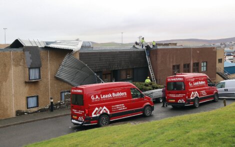 Two red vans parked in front of a building.