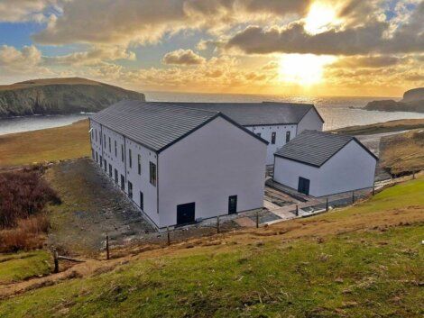 A white building sits on top of a hill overlooking the ocean.