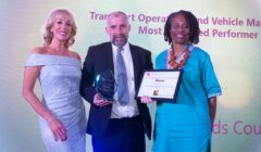 Three people are posing for a picture with an award.