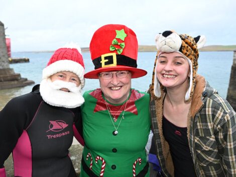 Three women in santa hats posing for a photo.