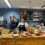 Two women standing in front of a counter with food.