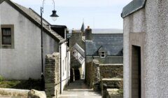 A narrow street lined with stone buildings and a lamp post.