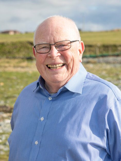 A man in a blue shirt standing in a field.