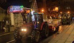 A tractor driving down a street with lights on it.