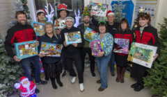 A group of people standing in front of a christmas tree.