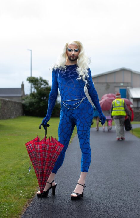 A woman in a blue costume holding an umbrella.