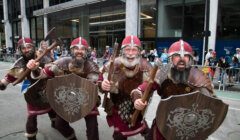 Three vikings dressed in armor walking down the street.