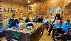 A group of people sitting around a table in a cabin.