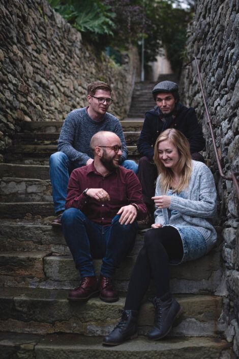 Four people sitting on steps in an alleyway.