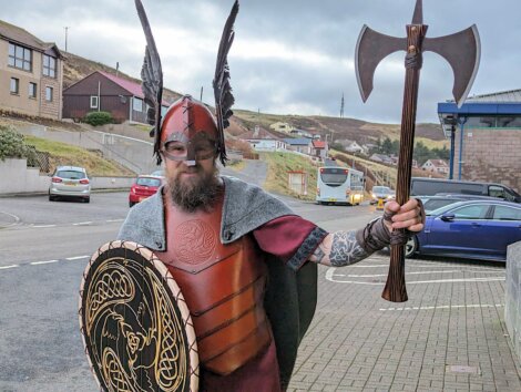 A man dressed as a viking holding an axe and shield.