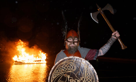 A man holding an axe in front of a fire.