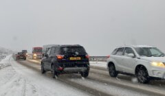 A group of cars driving on a snowy road.