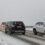 A group of cars driving on a snowy road.