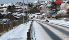 A road with cars on it and houses on the side.