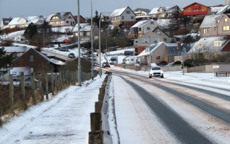 A road with cars on it and houses on the side.