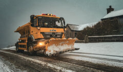 A snow plow driving down a snowy road.