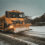 A snow plow driving down a snowy road.