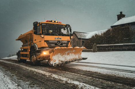 A snow plow driving down a snowy road.