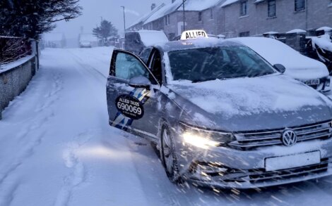 A silver volkswagen taxi driving down a snowy street.