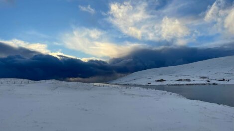 A snow covered hill under a cloudy sky.