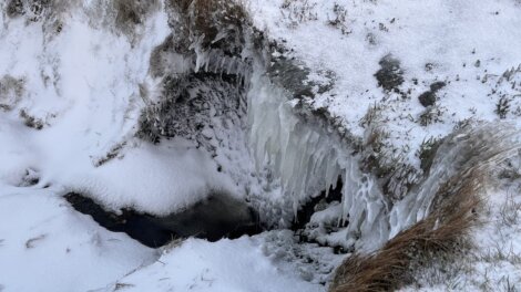 Icicles on the side of a snow covered hill.