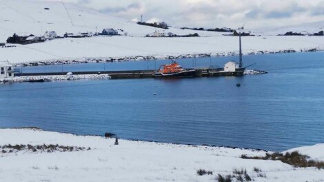 A snowy scene with a boat in the water.