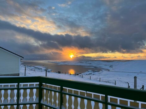 The sun is setting over a snow covered deck.