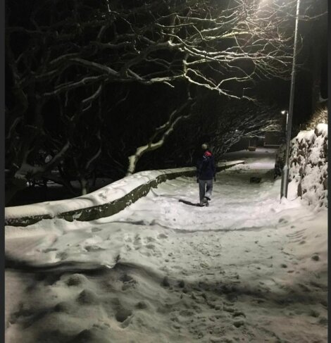 A person walking down a snow covered path at night.