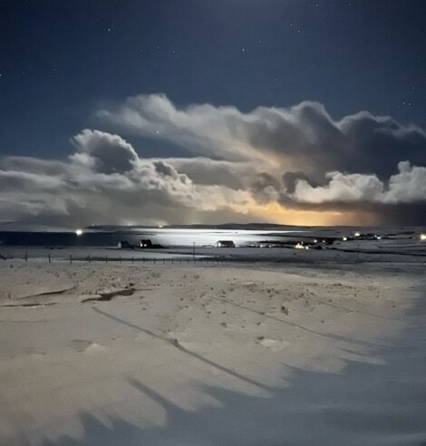 A full moon over a snow covered beach.