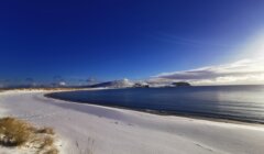 A beach covered in snow on a sunny day.