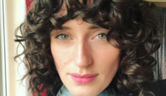 A woman with curly hair is posing for a photo.