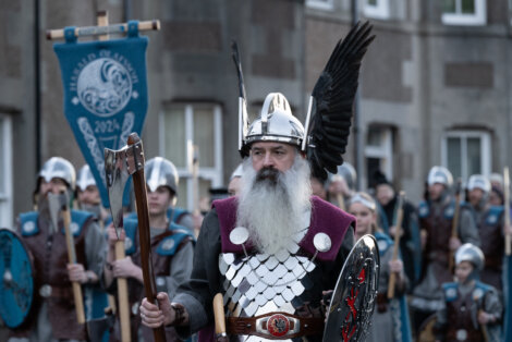 A man in a viking costume is walking down the street.