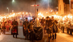 A group of people with torches walking down a street.