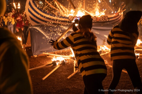 A group of people holding fire in front of a boat.